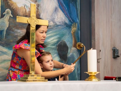 Girl and woman lighting candle in Chapel