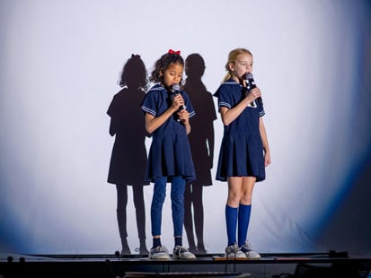 Two SLES girls in uniform on stage