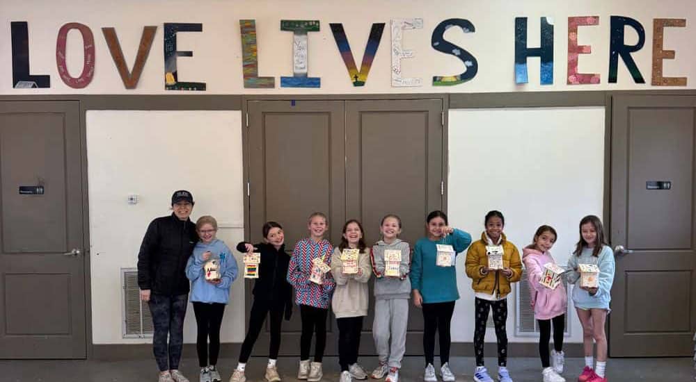 Private school students with a sign that says Love Lives Here